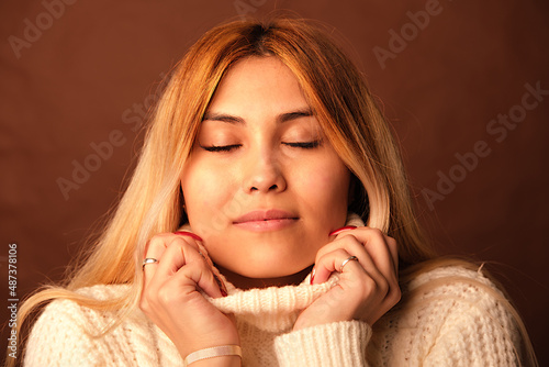 A woman of Asian appearance on a brown background