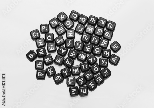letters of the russian alphabet on black chips are scattered on a white isolated background, top view