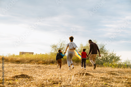 Black family flying kite while running together