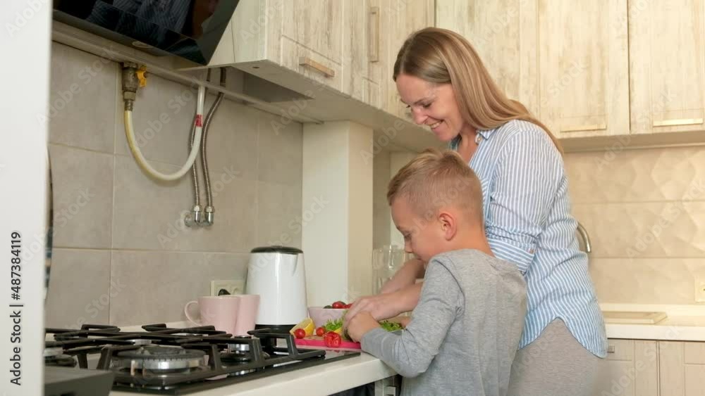 Pregnant mom with kid playing together and huging in the kitchen. Mother with son sharing good emotions while having breakfast at home.