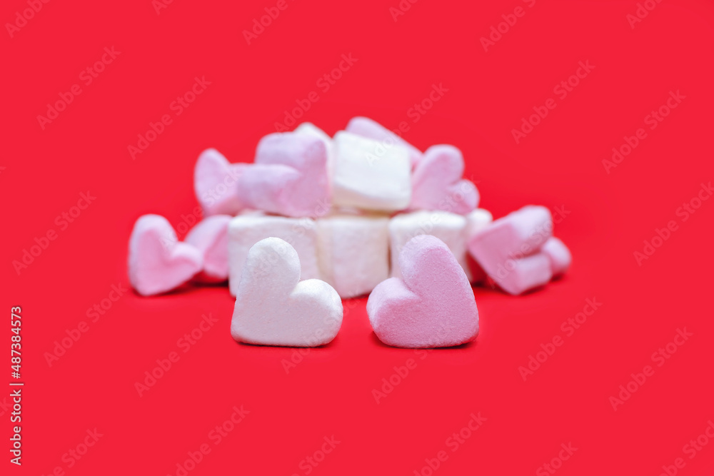 Zephyr in the shape of a heart on a red background. White and pink marshmallows as an image of love. Valentine's day concept in the form of a sweet marshmallow on a pink background Zephyr in the shape of a heart on a red background. White and pink marshmallows as an image of love. Valentine's day concept in the form of a sweet marshmallow on a pink background