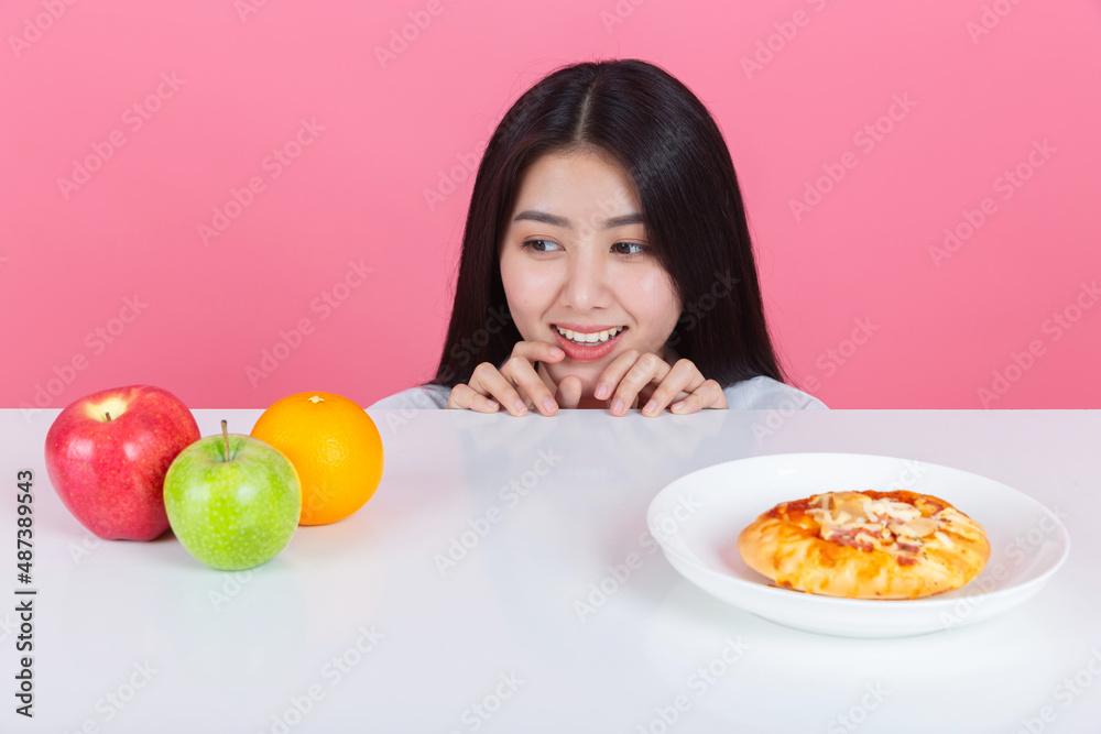 happy young asian woman choose to eat fresh orange apple fruits with copy space pink background, health care eat vegetables and useful foods lifestyles concept. happy young asian woman choose to eat fresh orange apple fruits with copy space pink background, health care eat vegetables and useful foods lifestyles concept.
