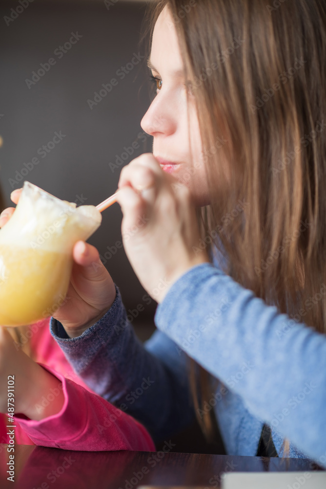 A beautiful young girl drinks a juice cocktail with ice cream in a cafe. A beautiful young girl drinks a juice cocktail with ice cream in a cafe.
