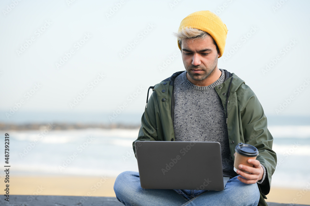 Hispanic man working on his laptop outdoors.