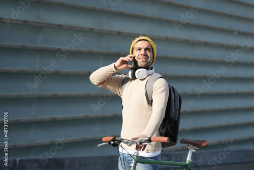 Hispanic hipster talking on phone and holding bicycle. Urban mobility concept.