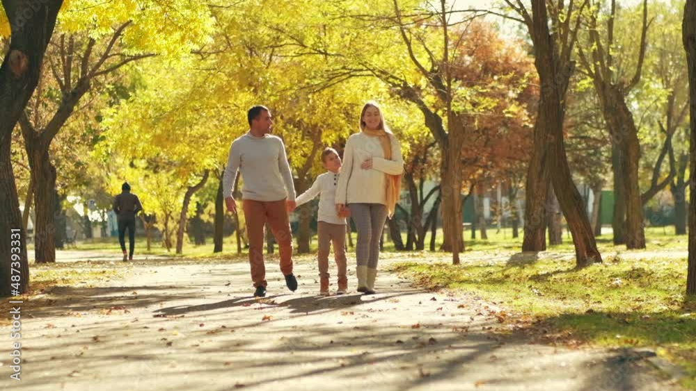 Young family, parents with their son are resting, walking in the park in white knitted sweaters, happy, smiling together. Young family, parents with their son are resting, walking in the park in white knitted sweaters, happy, smiling together.