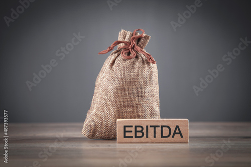 Money bag with a text EBITDA on wooden block. photo