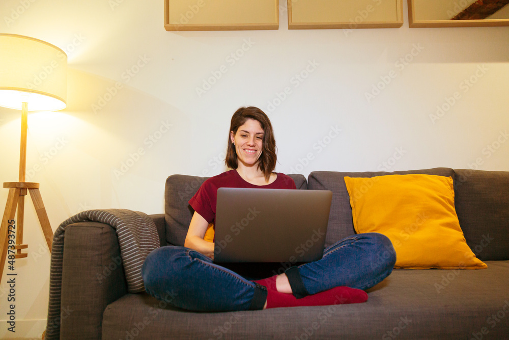 woman smiling on the sofa with a laptop woman smiling on the sofa with a laptop
