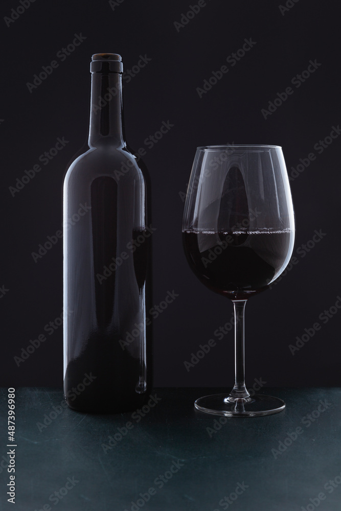 A red wine bottle without label and a full glass A red wine bottle without label and a full glass