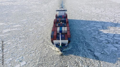 St. Petersburg, Russia, winter 2022: container ship goes through the ice floes, aerial view