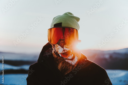 Athlete wearing buff goggles and snow jacket on the mountain at sunset