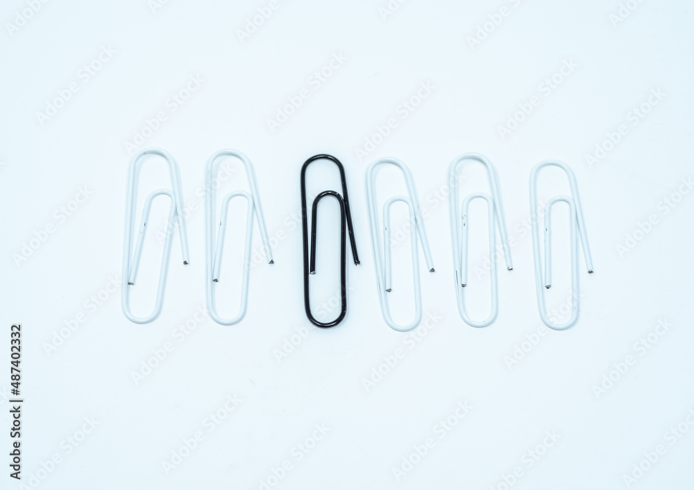 Obraz premium Odd black paper clip in a line of six