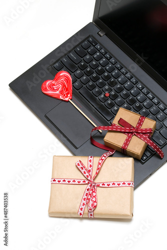 vertical photo. laptop, two gift boxes, heart shaped lollipop on white background.card, congratulations on Valentine's Day, Mother's Day. romantic background 