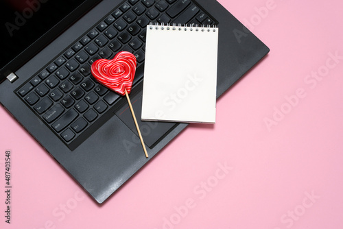laptop, notepad, heart shaped lollipop on pink background. card, congratulations on Valentine's Day, Mother's Day. romantic background