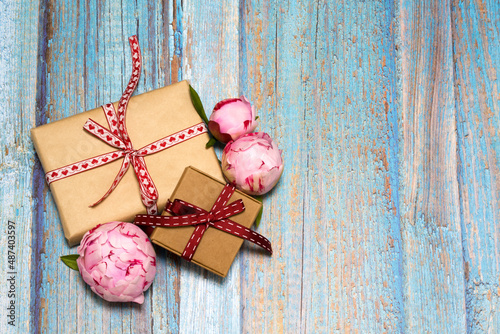 gift boxes, pink peonies on a blue wooden background