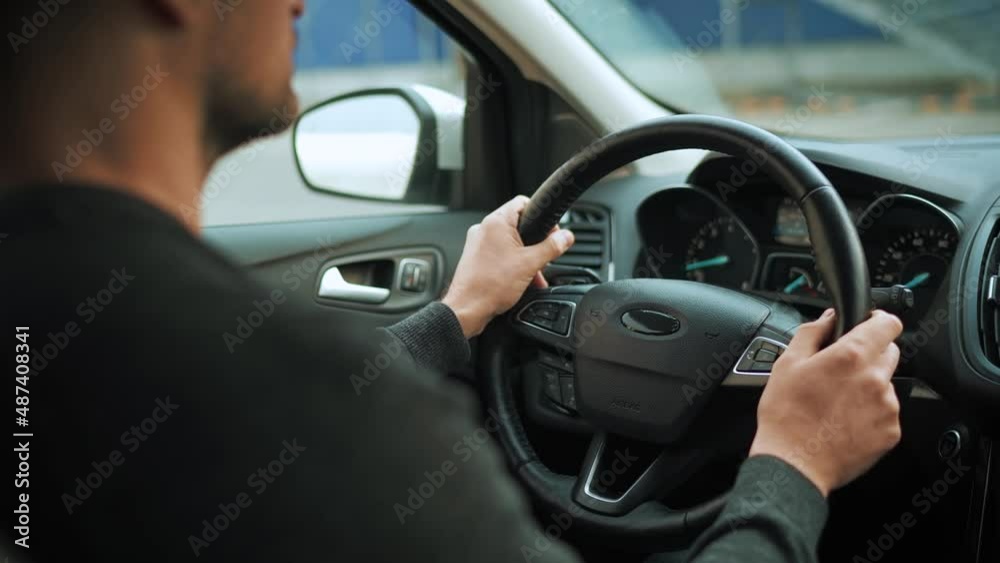 Man driving in innovative automated car using self-parking autopilot for parking on parking lot. Rear view from behind the driver's shoulder Man driving in innovative automated car using self-parking autopilot for parking on parking lot. Rear view from behind the driver's shoulder