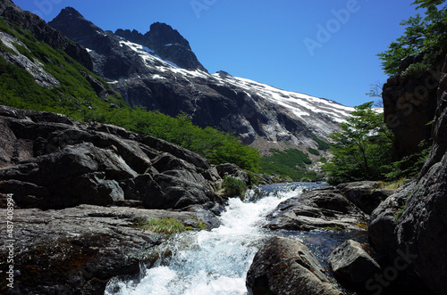 Mountain river in Patagonia, white water bare black rock green bushes snow hills sunny day in Argentina Nahuel Huapi National Park, Nature landscape