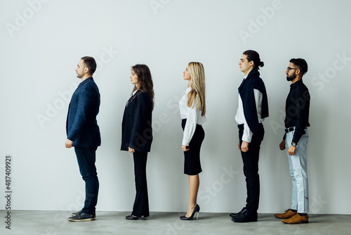Long line of diverse professional business people standing in a queue in profile isolated on white background