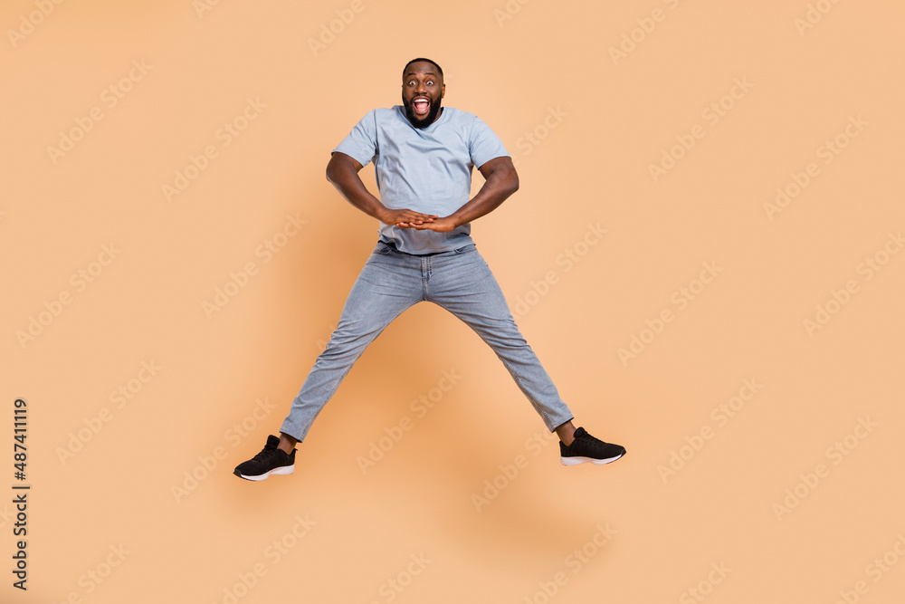 Full length body size view of attractive cheerful guy jumping good mood fooling isolated over beige pastel color background Full length body size view of attractive cheerful guy jumping good mood fooling isolated over beige pastel color background