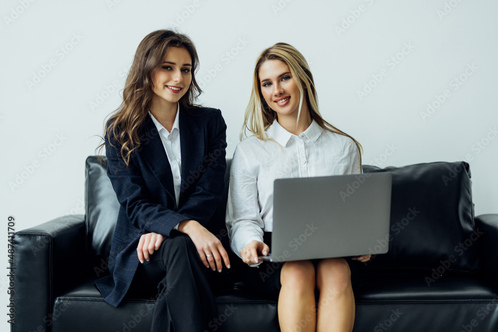 Two business people sitting in the couch discussing over laptop in office Two business people sitting in the couch discussing over laptop in office