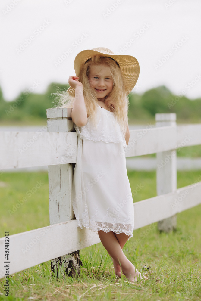 Beautiful little blonde girl on a ranch on a summer day.