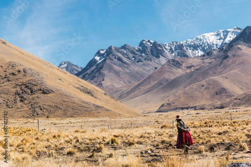 indigenous women walking dressed in typical dress made of alpaca fiber on a sunny day surrounded by clouds and a blue sky