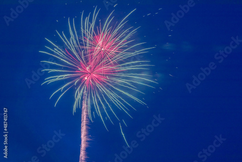 A volley of festive multi-colored fireworks against the blue sky.