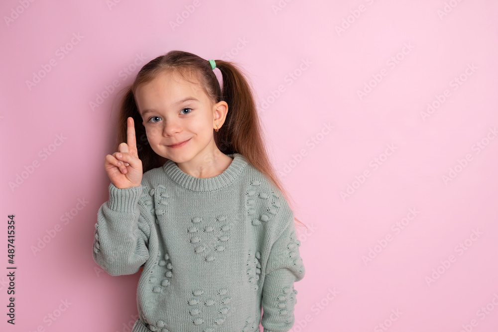 Portrait of a cute pretty girl with ponytails in a green jumper on a pink colored background. Space for text. Portrait of a cute pretty girl with ponytails in a green jumper on a pink colored background. Space for text.