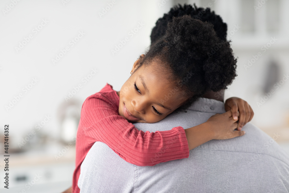 Obraz premium Smiling little black girl hugging her daddy