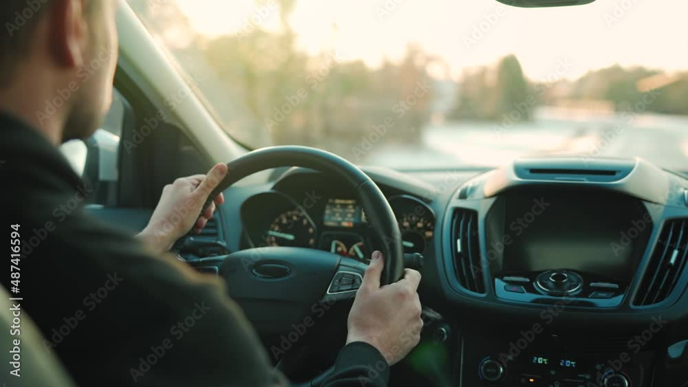 Man drives a car along the road, the setting sun shines in the windshield Man drives a car along the road, the setting sun shines in the windshield