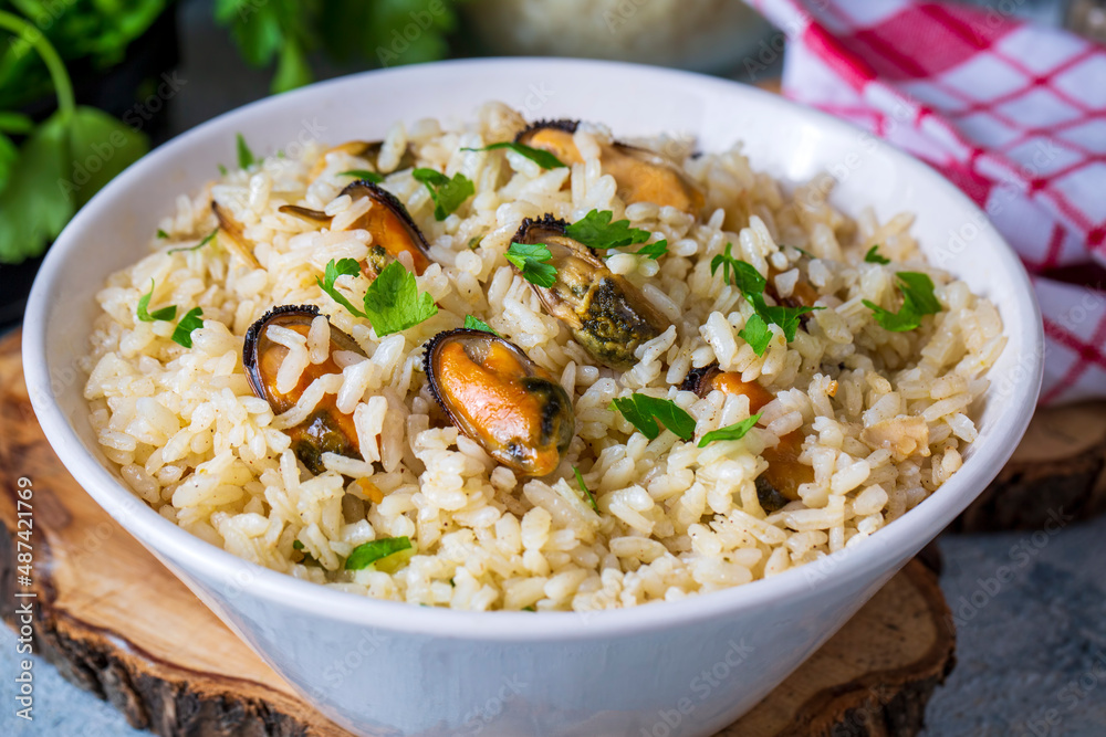 Mussel rice pilaf. Rice with mussels on small white plate on ceramic.