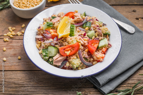 Food dieting concept, tuna salad. Couscous salad with conserved tuna, tomatoes, cucumbers and purple onions on table. Copy space.