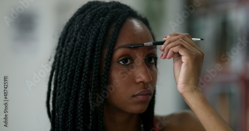 African black teen girl applying make-up in front of mirror
