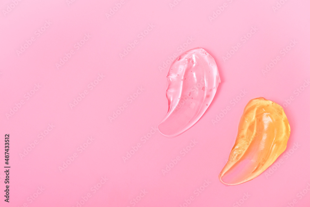 Gel cosmetic smears for skin care on a pink background, cream, peeling, milk, lotion, drops texture. Closeup with copy space.