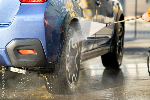 Closeup of male driver washing his car with contactless high pressure water jet in self service car wash