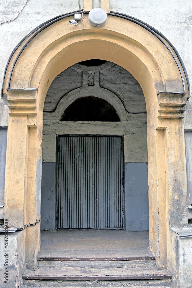 one gray wooden door on a brown concrete wall of a historic building