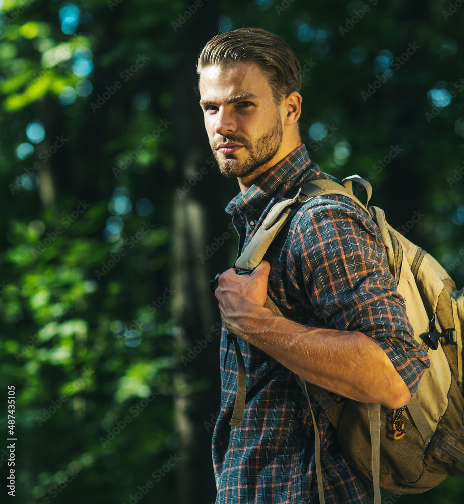 Male hiker with backpack walking in forest. Bearded man enjoy hike in summer mountains on sunny day. Male hiker with backpack walking in forest. Bearded man enjoy hike in summer mountains on sunny day.