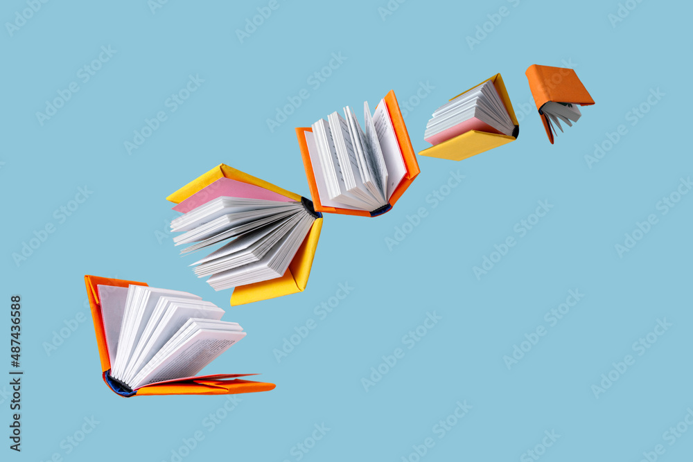 books in colored covers swirl on a blue background, copy space - obrazy, fototapety, plakaty 