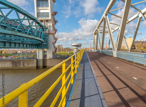 Obraz na płótnie Cycle path on the Algera Bridge over the Hollandse IJssel river. The bridge connects Capelle aan den IJssel and Krimpen aan den IJssel. The blue strip is for walkers. On the left is the storm barrier. w salonie