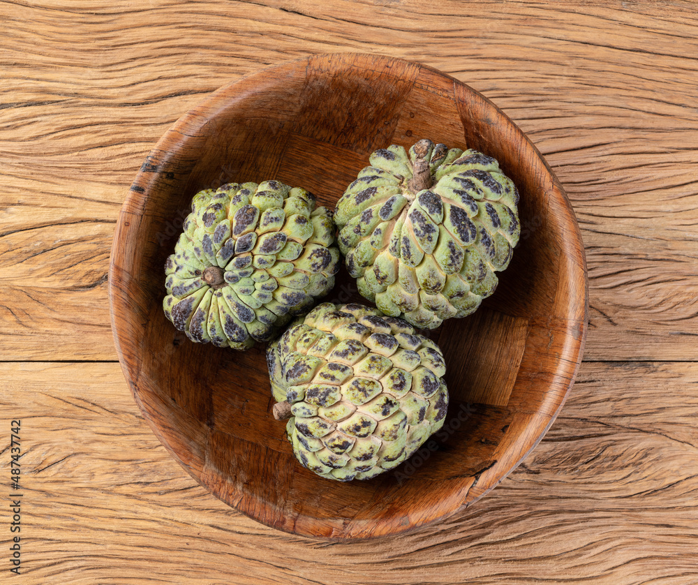Fototapeta premium Sugar apples or custard apples in a bowl over wooden table