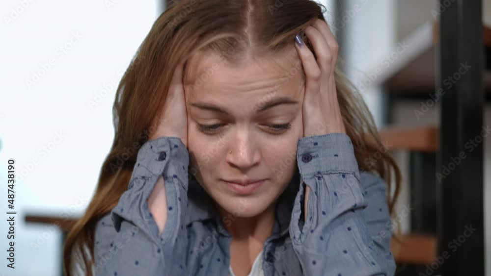 Headshot stressed teenage girl with panic attack breathing heavily looking at camera holding head in hands. Front view close-up portrait of anxious worried Caucasian teenager posing indoors at home Headshot stressed teenage girl with panic attack breathing heavily looking at camera holding head in hands. Front view close-up portrait of anxious worried Caucasian teenager posing indoors at home