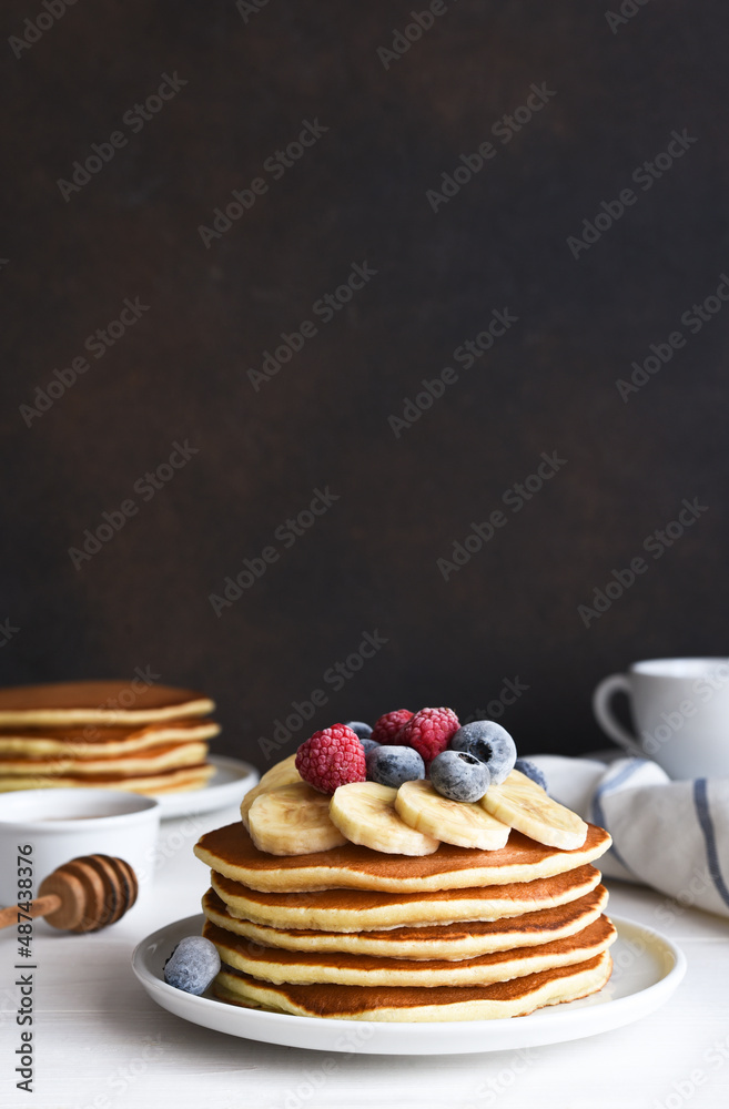Stack of pancakes with berries and syrup on a kitchen table for breakfast. Good morning
