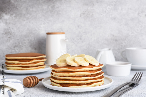 Stack of honey and banana pancakes on the kitchen table for breakfast.