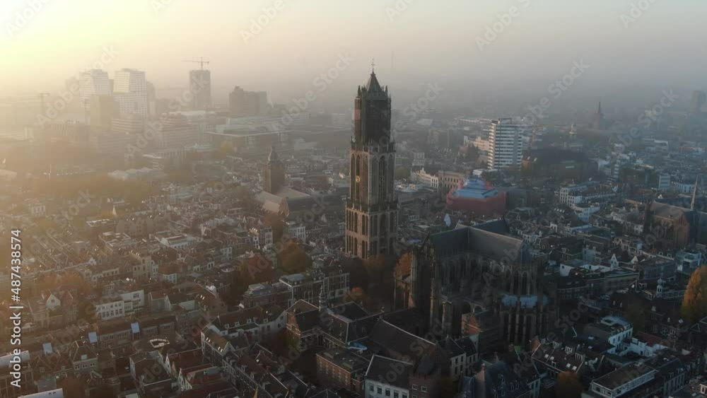 Cinematic aerial video of Utrecht historic city center with Dom church and foggy golden light 