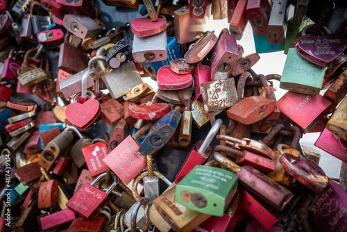 many small padlocks with names of couples hang as a symbol of love
