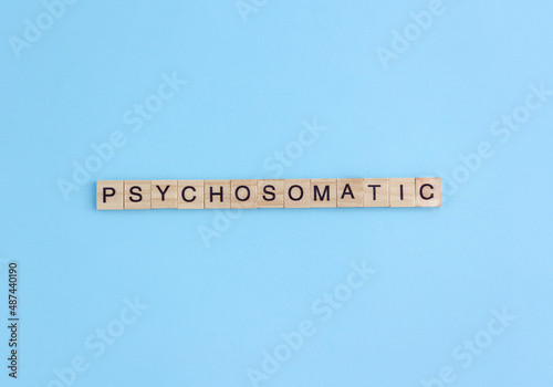 Word Psychosomatic on wooden blocks with letters on blue background. Minimal concept, flat lay
