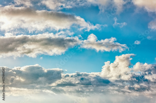 Daytime blue sky Background with white cumulus and tiny clouds. Soft focus.