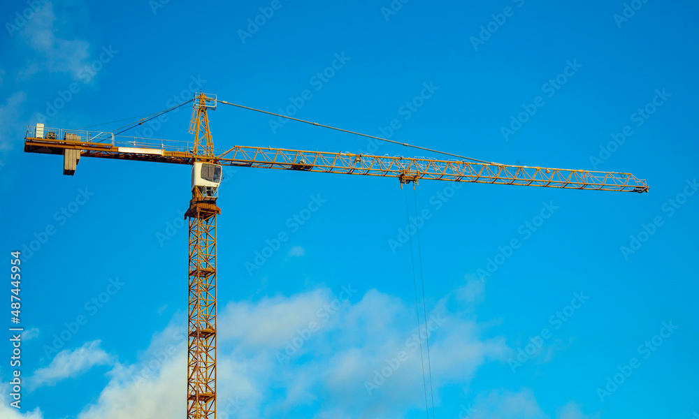 Tower with cabin and an arrow of  working construction crane on  blue sky background.