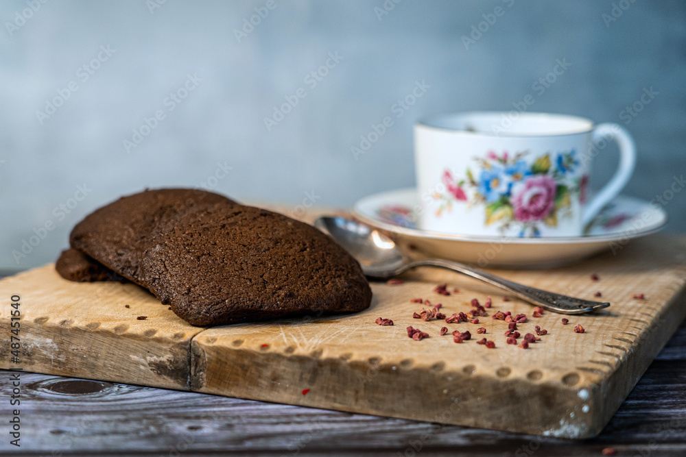 A cup of black tea with chocolate cookies on a wooden plate A cup of black tea with chocolate cookies on a wooden plate
