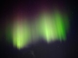 Green and red aurora borealis on night sky